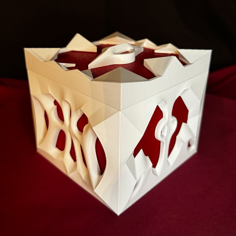 May include: White 3D printed box with a red interior and intricate geometric designs. The box has a lid with a raised design.