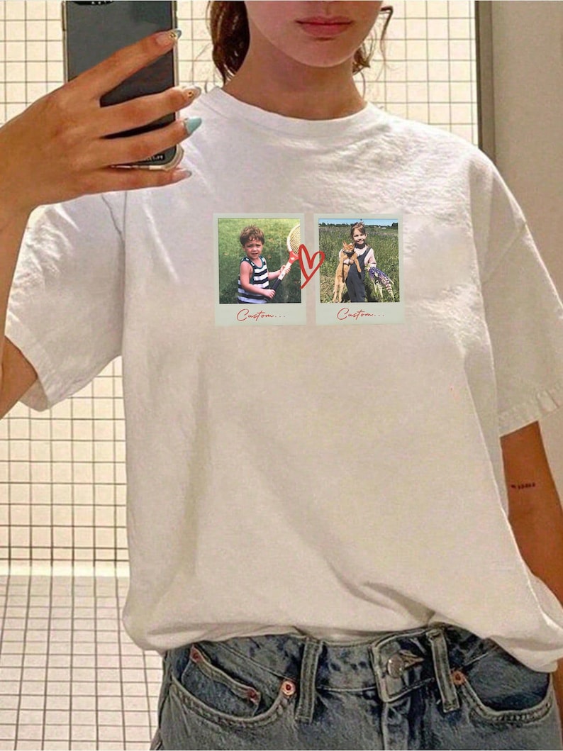 May include: White t-shirt featuring two polaroid-style photos connected by a red heart. The photos show children in outdoor settings. The word "Custom..." is printed below each photo. The shirt is made of a soft, comfortable material.