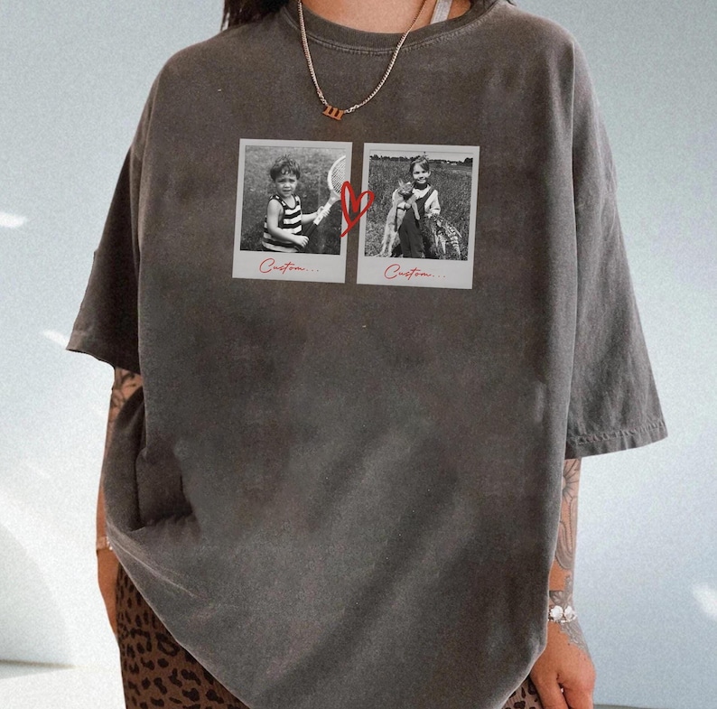May include: Dark gray t-shirt featuring two black and white Polaroid-style photos connected by a red heart graphic. The photos depict children. The word "Custom..." is printed below each photo. The shirt has short sleeves and a relaxed fit.