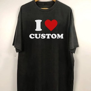 Op de afbeelding: Zwart T-shirt met een witte afbeelding met de tekst "I &hearts; CUSTOM".
