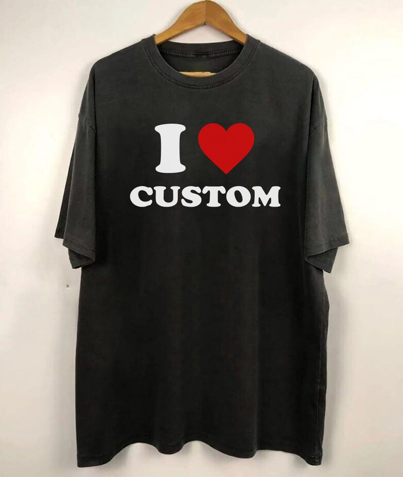 Op de afbeelding: Zwart T-shirt met een witte afbeelding met de tekst "I &hearts; CUSTOM".