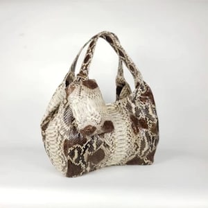 Op de afbeelding: Een bruine en witte slangenleren handtas met twee handvatten.