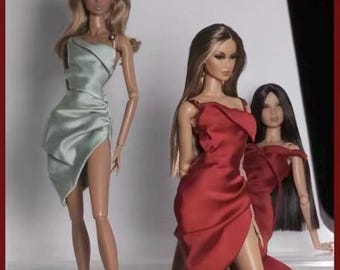 May include: Three fashion dolls wearing elegant dresses. The doll on the left is wearing a light green dress with a side slit. The doll in the center is wearing a red dress with a side slit. The doll on the right is wearing a red dress with a side slit and has long black hair.