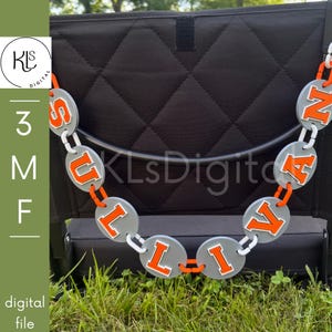 May include: A decorative chain made of gray circular links, each featuring a bright orange letter that spells out the name SULLIVAN. The links are connected by small orange plastic connectors, forming a hanging display against a black background.
