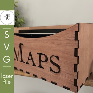 May include: A wooden box with the word "MAPS" etched on the front. The box is made of light brown wood and has a curved top. The side of the box has a series of interlocking joints. The image also includes the text "SVG laser file".