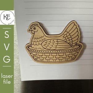 May include: Wooden laser-cut hen in a basket design. The hen is detailed with etched feathers and a comb. The basket has a woven pattern. The image also includes the text "SVG laser file".