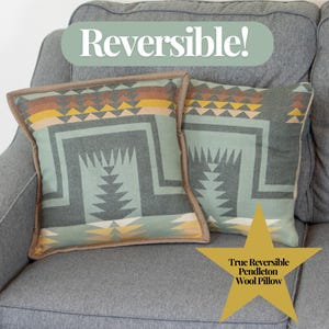 May include: Two reversible Pendleton wool pillows with geometric patterns in shades of gray, teal, yellow, and brown. The pillows have a tan border and are displayed on a gray couch. The text "Reversible!" and "True Reversible Pendleton Wool Pillow" are visible.