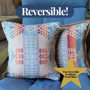 May include: Two reversible Pendleton wool pillows with geometric patterns in shades of blue, orange, and cream. The pillows are on a blue chair. Text on the image reads "Reversible!" and "True Reversible Pendleton Wool Pillow."