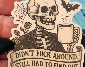 Puede incluir: Una pegatina con un esqueleto con traje sosteniendo una taza de café, con un diseño de murciélago y telaraña. La pancarta dice: "DIDN'T FUCK AROUND. STILL HAD TO FIND OUT. RUDE."