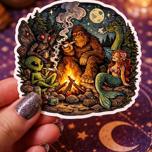 May include: A colorful sticker featuring a campfire scene with a Bigfoot, alien, mothman, mermaid, and a lake monster. The characters are smoking around a fire under a starry night sky with a full moon. The sticker is held by a hand.