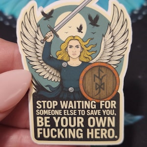 May include: A sticker featuring a blonde warrior with a sword and shield, wings, and the text "STOP WAITING FOR SOMEONE ELSE TO SAVE YOU, BE YOUR OWN FUCKING HERO." The design includes birds and a moon.