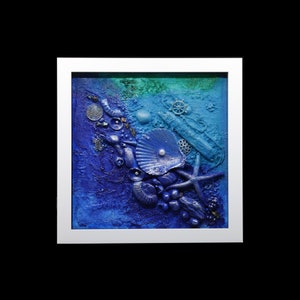 May include: A framed blue and green mixed media artwork featuring a seashell, starfish, and other ocean-themed elements.