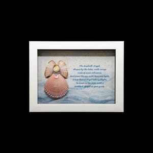 May include: A framed artwork featuring a seashell angel. The angel is made from seashells, with a pink shell body, tan shell wings, and pearl embellishments. The background depicts a blue and white ocean scene with handwritten text.
