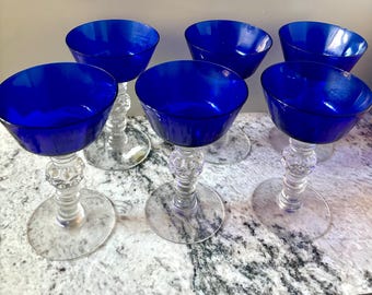 May include: Set of six cobalt blue glass stemmed cocktail glasses with clear glass stems and bases.