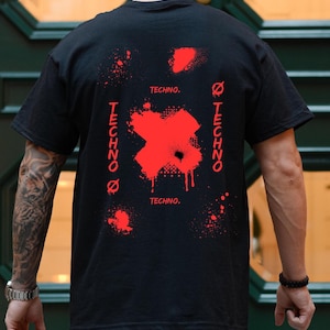 Puede incluir: Camiseta negra con un diseño gráfico rojo en la espalda. El diseño incluye una gran X roja con efectos de salpicaduras de pintura y la palabra "TECHNO" en rojo, repetida vertical y horizontalmente.