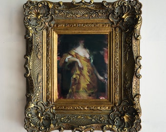 Könnte beinhalten: Ein gerahmtes Gemälde einer Frau in einem gelben Kleid, vor einem dunklen Hintergrund. Der Rahmen ist verziert und golden.