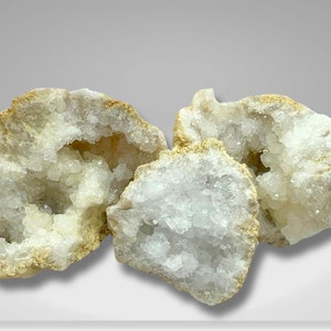May include: Three natural geode crystals with a white, sparkly interior and a tan, rough exterior.