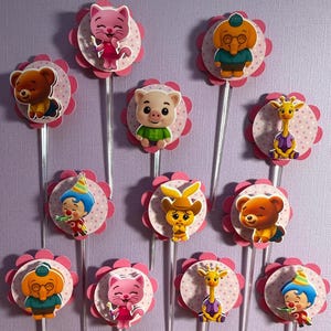 Pu&ograve; includere: Una collezione di decorazioni per cupcake colorate con vari personaggi di animali dei cartoni animati. Ogni decorazione ha un bordo smerlato rosa e un bastoncino di plastica trasparente. I personaggi includono un orso, un gatto, un maiale, una giraffa e un clown.
