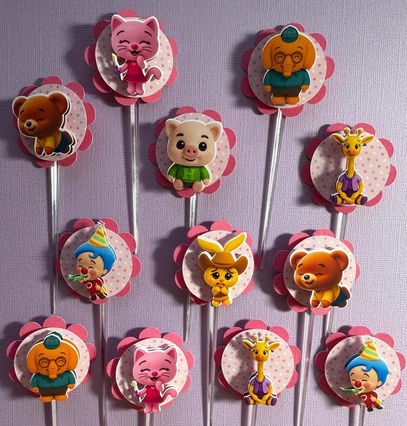 Pu&ograve; includere: Una collezione di decorazioni per cupcake colorate con vari personaggi di animali dei cartoni animati. Ogni decorazione ha un bordo smerlato rosa e un bastoncino di plastica trasparente. I personaggi includono un orso, un gatto, un maiale, una giraffa e un clown.