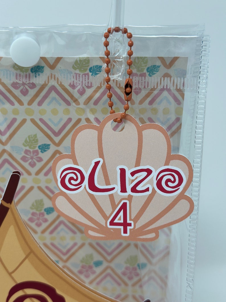 Może przedstawiać: Jasnobrązowa etykieta w kształcie muszli z czerwonym wzorem spiralnym i tekstem "@Lizo 4" w kolorze czerwonym.