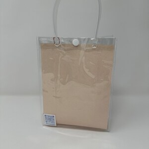 Może przedstawiać: Przezroczysta plastikowa torba z białym zapięciem na guzik i brązową wkładką papierową. Torba ma przezroczysty plastikowy uchwyt.