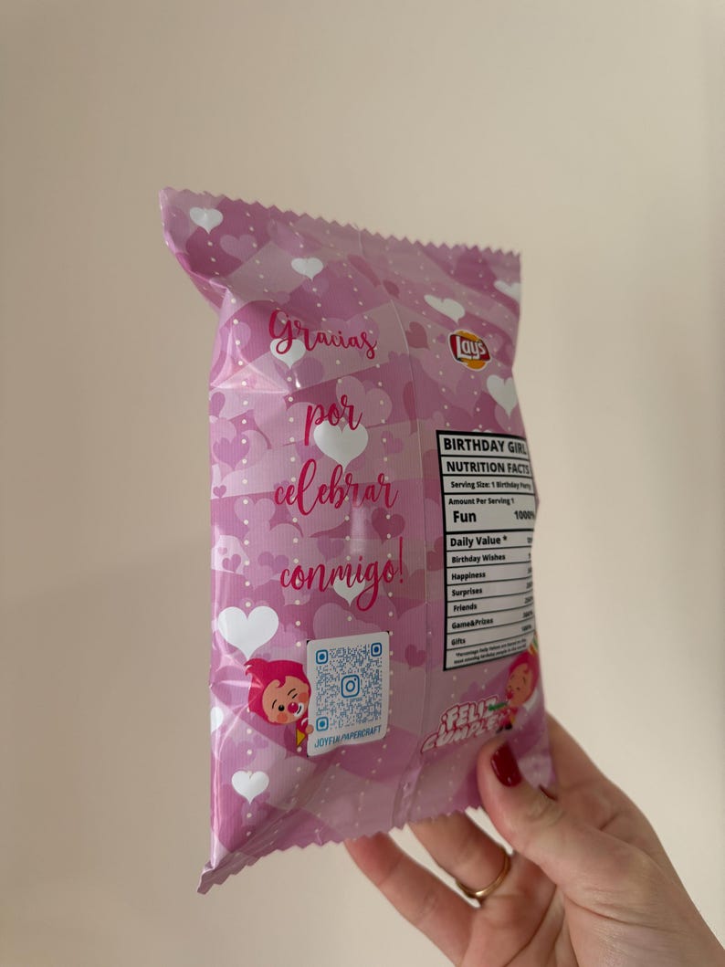 May include: A pink Lay's potato chip bag with white hearts and text in Spanish. The text reads "Gracias por celebrar conmigo!" and "Felicidades". The bag also has a QR code and a cartoon character.