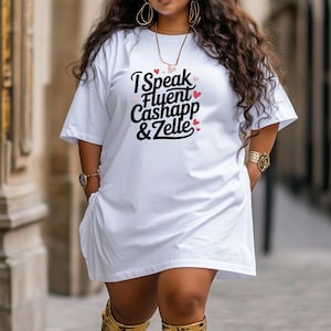 May include: White oversized t-shirt with the text "I Speak Fluent Cashapp & Zelle" printed in black with pink hearts.