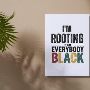Puede incluir: Un póster blanco con el texto "I'm rooting for everybody black" en letras negras, rojas, amarillas y verdes. Las letras tienen un aspecto desgastado y vintage.