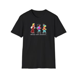 May include: Black t-shirt featuring a pixelated graphic of three figures in red, pink, and blue. The text "Always seek adventure" is below the figures. The shirt is made of a soft material.