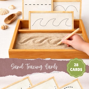 May include: A wooden sand tray with sand tracing cards. The cards feature dashed lines in different shapes. A hand uses a wooden stylus to trace a wave pattern in the sand. Text reads "Sand Tracing Cards" and "28 Cards".