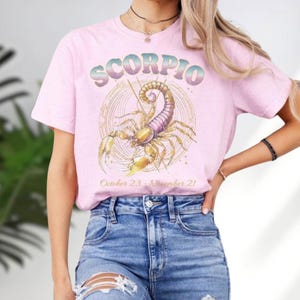 a woman wearing a pink scorpion t - shirt