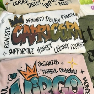 a pile of t - shirts sitting on top of a bed
