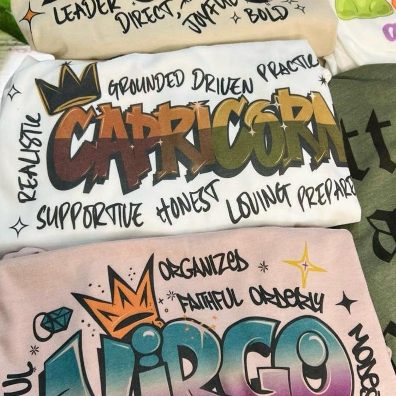 a pile of t - shirts sitting on top of a bed