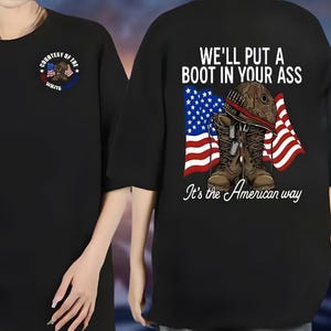 May include: Black t-shirt with a graphic on the back featuring combat boots, a helmet, and the American flag. The text reads "WE'LL PUT A BOOT IN YOUR ASS" and "It's the American way." The front has a smaller design with text and an American flag.