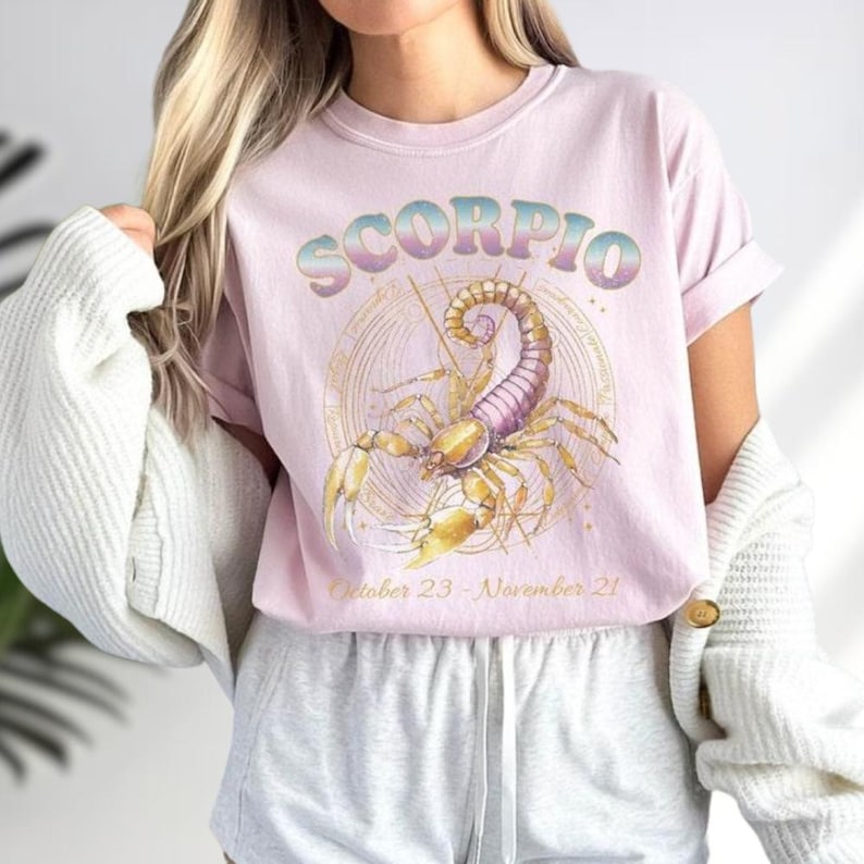 a woman wearing a pink scorpion t - shirt
