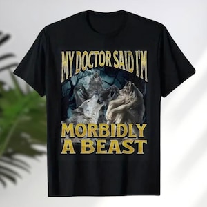 a black t-shirt with a graphic design depicting two wolves and the text "MY DOCTOR SAID I'M MORBIDLY A BEAST" printed on it.