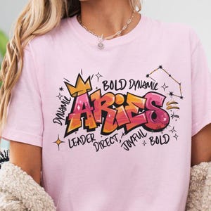 a woman wearing a pink t - shirt with the word arras on it