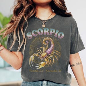 a woman wearing a scorpion t - shirt and jeans