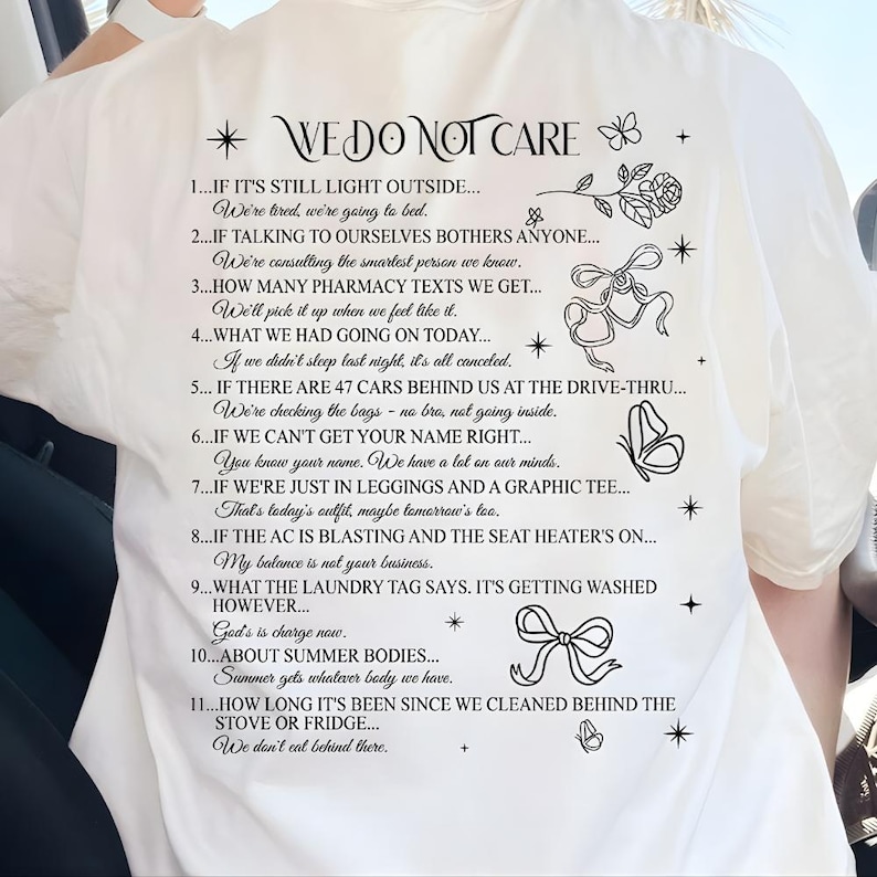 May include: White graphic tee with the text "WE DO NOT CARE" and a list of humorous statements. The design includes floral and butterfly illustrations. A casual, comfortable style.