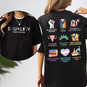 May include: Black t-shirt with the text "EQUALITY HURTS NO ONE" and various graphic symbols. The back of the shirt features multiple icons and phrases, including "Black Lives Matter," "Love is Love," and "Trans Rights are Human Rights."