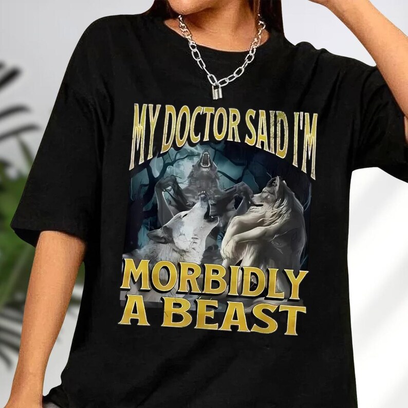 a black t-shirt with a graphic design depicting three wolves and the text "MY DOCTOR SAID I'M MORBIDLY A BEAST" printed on it.