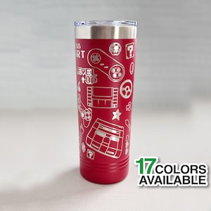 May include: Red stainless steel tumbler with a laser engraved design of retro video game controllers, game cartridges, and other gaming icons. The tumbler has the text "Level Up" on it. 17 colors available.