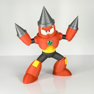 May include: A red and black action figure of a robot character with a drill-shaped helmet and arm attachments. The figure has yellow accents, a green emblem, and is posed with arms outstretched.