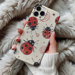 May include: A phone case featuring a cream-colored background with a repeating pattern of red ladybugs, black antennae, and red spiral and star accents. The case has a glossy finish and is designed to fit a smartphone.