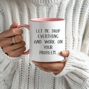 Könnte beinhalten: Weiße Keramik-Kaffeetasse mit rosafarbenem Rand. Die Tasse hat einen schwarzen Text mit der Aufschrift "Lass mich alles fallen lassen und an deinem Problem arbeiten."