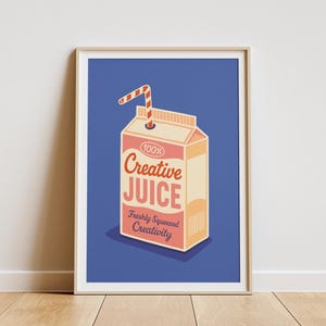 May include: Framed art print featuring a carton of "Creative Juice" with a straw. The carton is peach and cream-colored with red text and a blue background. The text reads "100% Creative Juice, Freshly Squeezed Creativity."