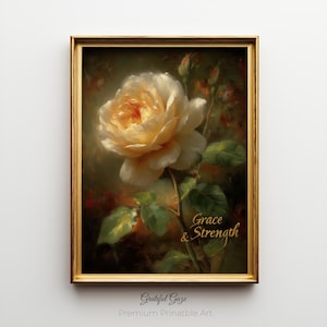 Puede incluir: Una impresión enmarcada con una pintura detallada de una rosa color crema con un centro amarillo, hojas verdes y las palabras "Grace & Strength". La obra de arte está en un marco dorado, con el texto "Grateful Gaze" y "Premium Printable Art" en la parte inferior.