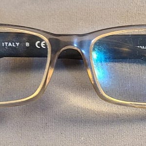 May include: Rectangular eyeglasses with a brown and tan frame and dark temples. The text "MADE IN ITALY" is visible on the frame. The lenses are clear. The glasses are designed for vision correction.