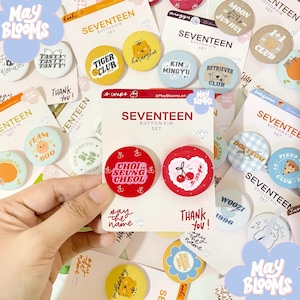 Könnte beinhalten: Eine Sammlung von SEVENTEEN-Anstecknadeln auf Karten. Die Anstecknadeln zeigen verschiedene Designs, darunter Text, Cartoon-Charaktere und die Wörter "TIGER CLUB" und "RETRIEVER CLUB". Auf den Karten steht der Text "SEVENTEEN BUTTON PIN SET".