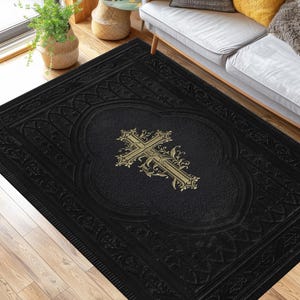 Può includere: Un tappeto rettangolare con sfondo nero tinta unita, un motivo a rilievo sul bordo e un design centrale a croce ornamentata color oro. Il tappeto presenta una superficie testurizzata ed è posizionato su un pavimento in legno chiaro.